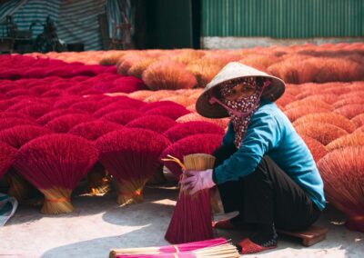 Woman bundling vibrant red incense bouquets - Hanoi, Vietnam